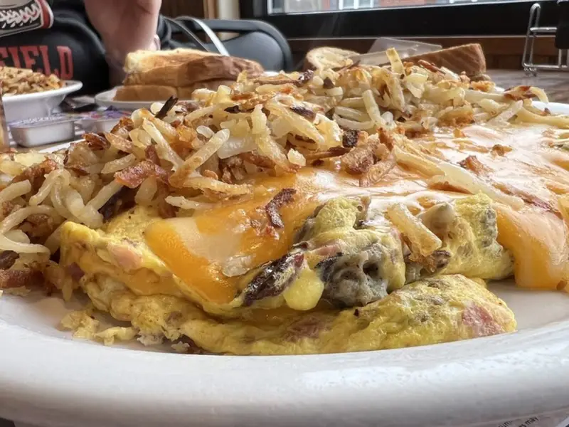 A plate of omelette with bacon and onions on it.